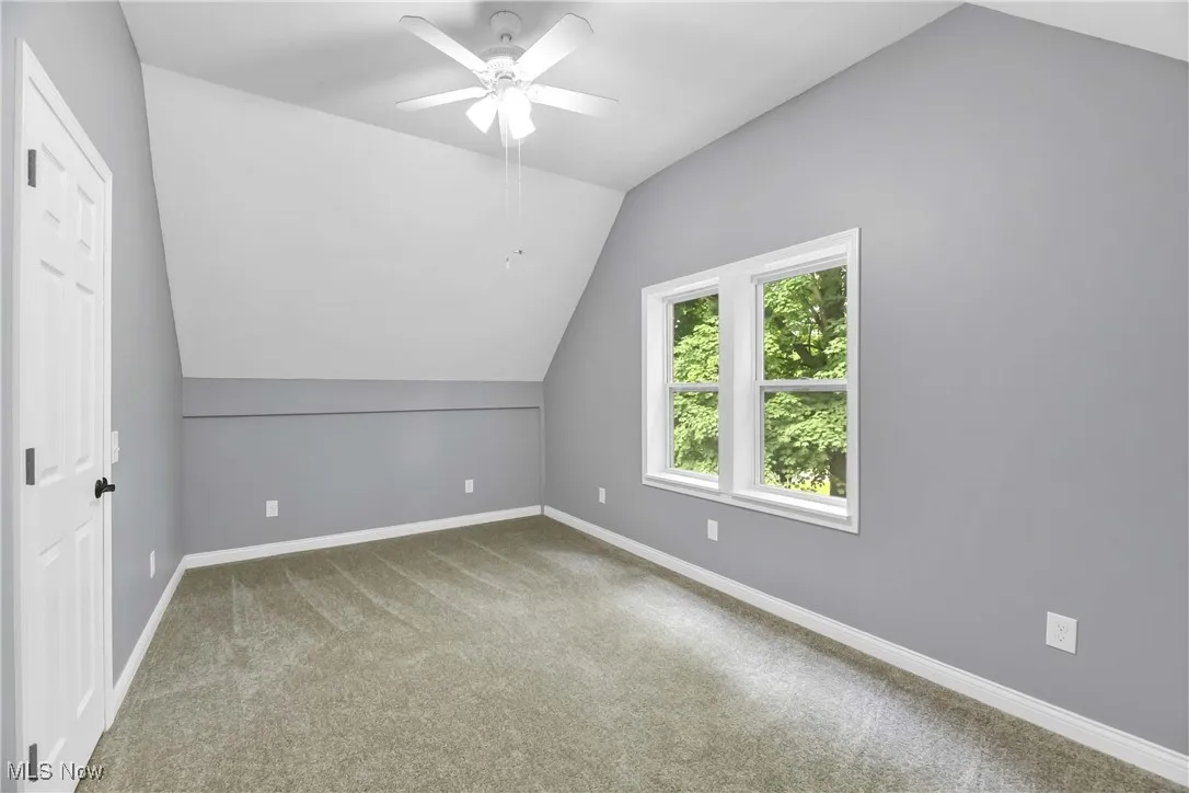 Additional living space with lofted ceiling, carpet flooring, and ceiling fan
