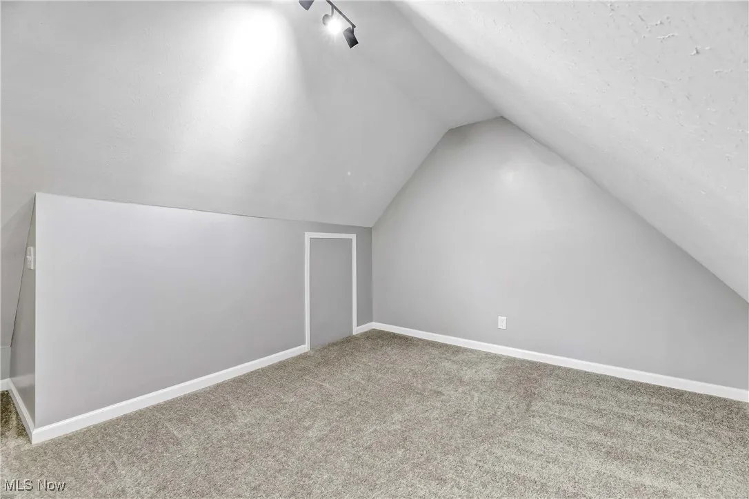 Bonus room with vaulted ceiling and carpet