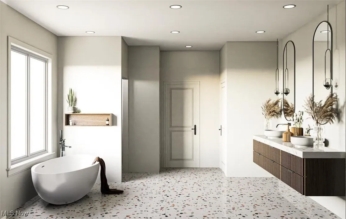 Bathroom featuring double vanity, a freestanding tub, and recessed lighting