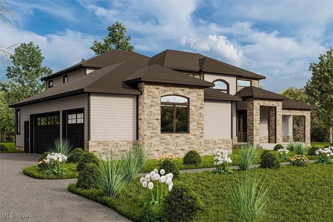 View of front of house featuring an attached garage, driveway, and stone siding