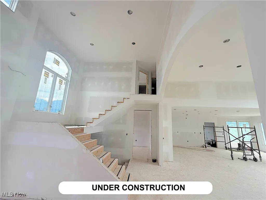Staircase featuring a towering ceiling and arched walkways