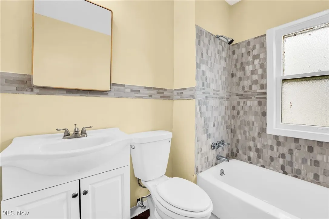 Bathroom featuring vanity, tile walls, shower / washtub combination, and wainscoting