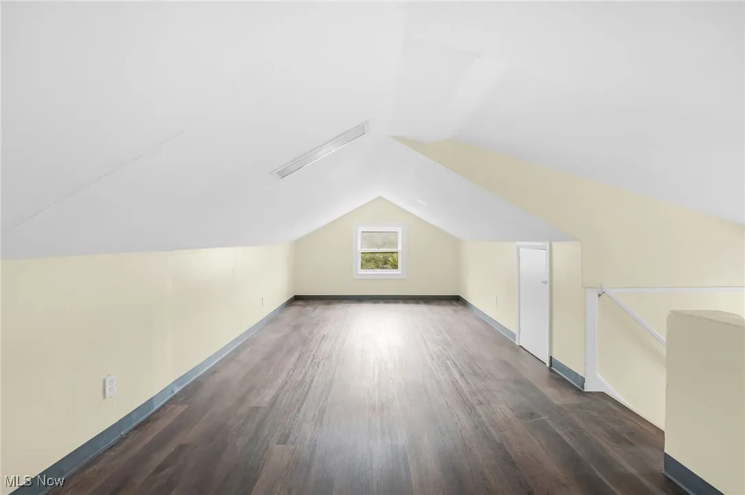 Additional living space featuring dark wood-style floors and lofted ceiling