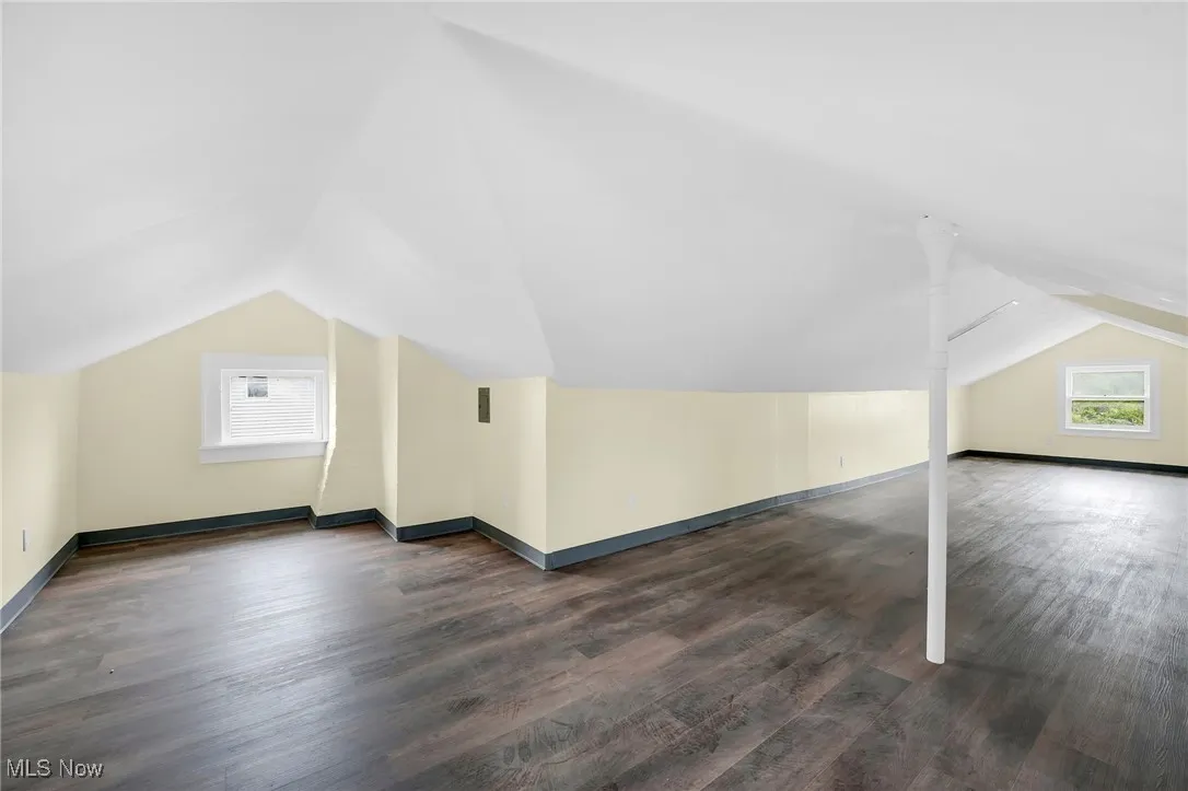 Additional living space featuring vaulted ceiling and dark wood finished floors