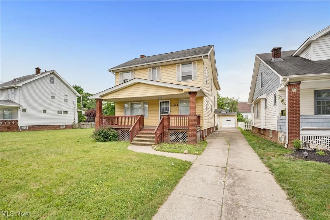 Traditional style home with covered porch, driveway, a front lawn, an outdoor structure, and a garage