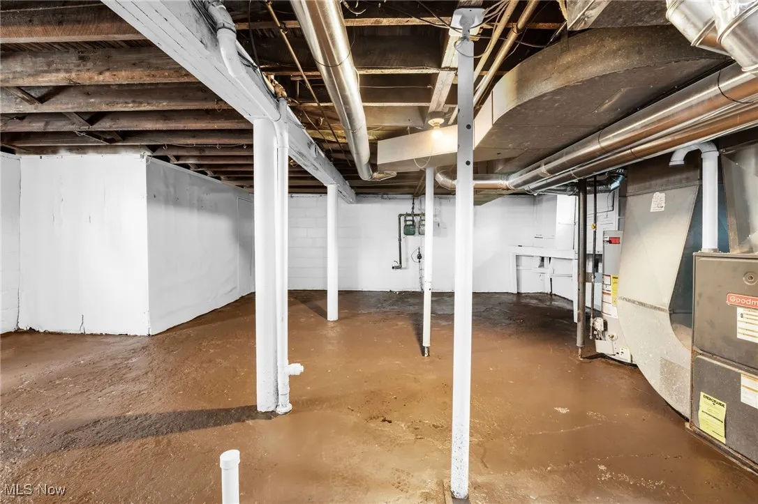 Unfinished below grade area featuring heating unit and gas water heater