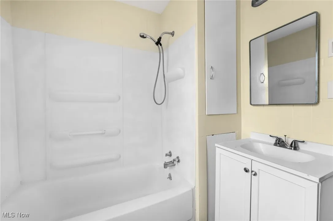 Bathroom with vanity, bathing tub / shower combination, and backsplash