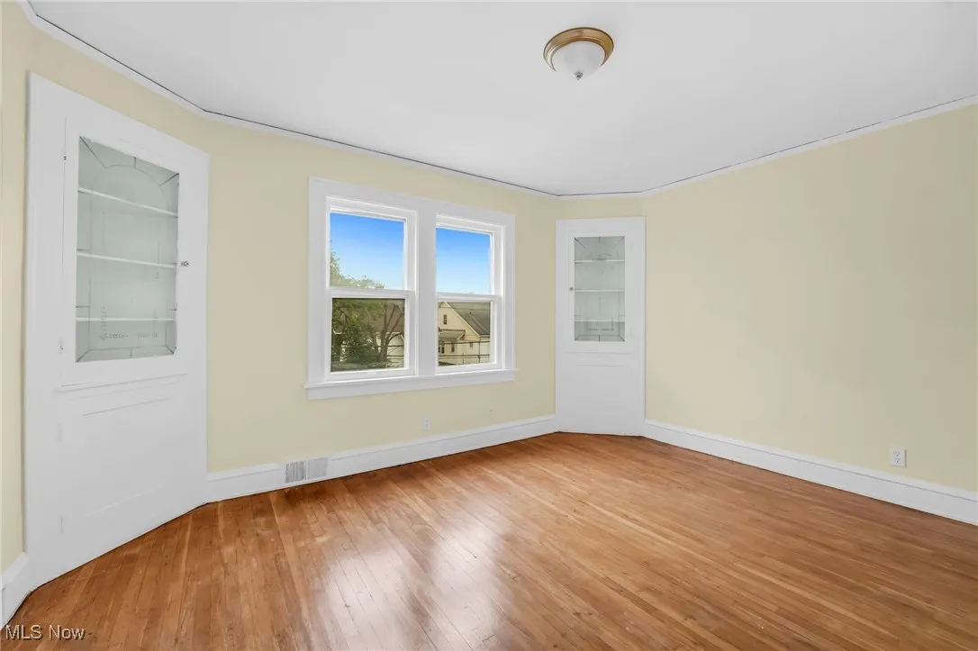 Empty room with hardwood / wood-style floors and crown molding