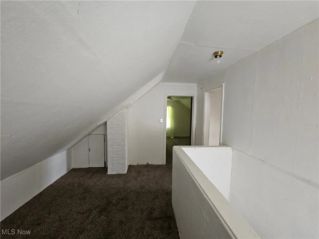 Additional living space with vaulted ceiling and dark carpet