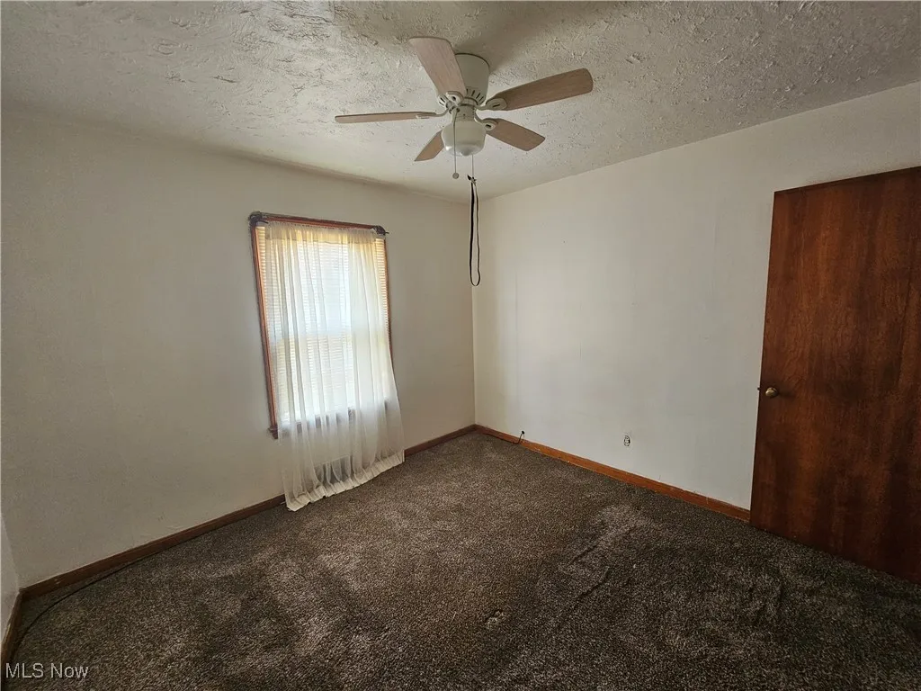 Carpeted spare room featuring ceiling fan and a textured ceiling