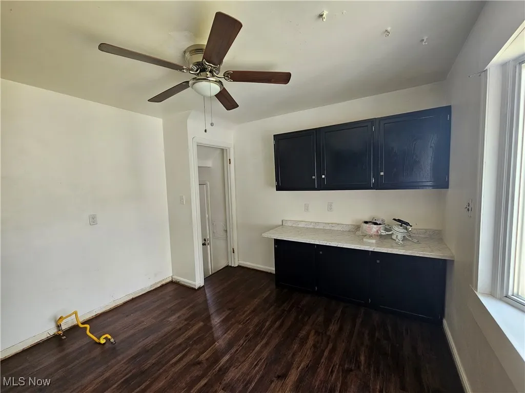 Kitchen with dark wood-style floors, light countertops, dark cabinetry, and a ceiling fan