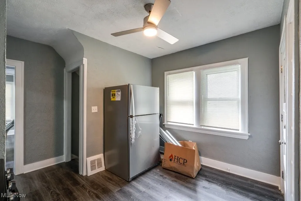 Kitchen with freestanding refrigerator, dark wood-type flooring, and a ceiling fan