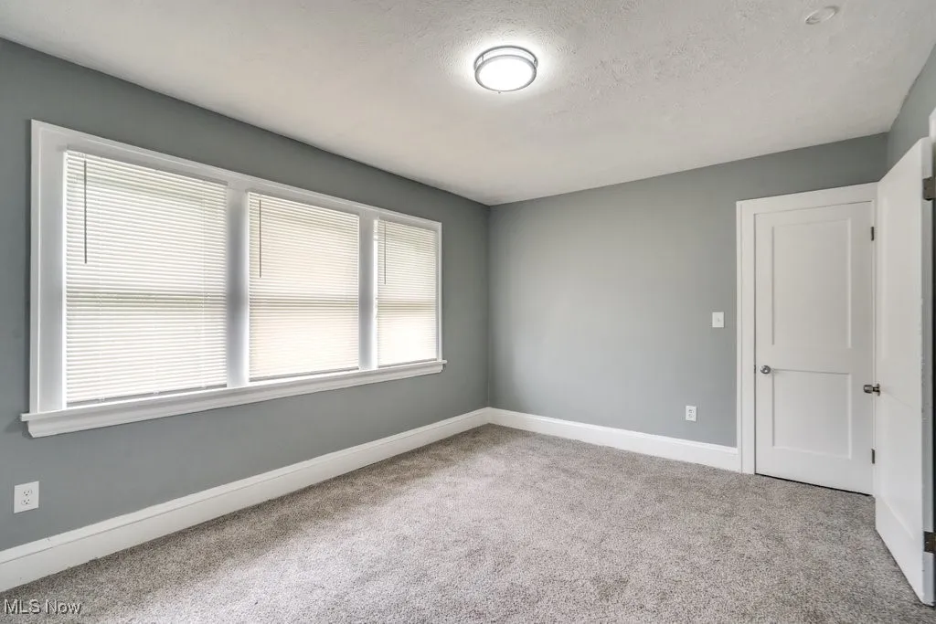 Carpeted spare room featuring baseboards and a textured ceiling