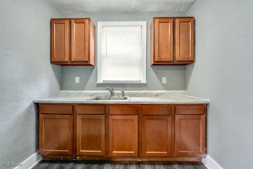 Kitchen featuring light countertops, brown cabinets, dark wood-style floors, and a textured ceiling