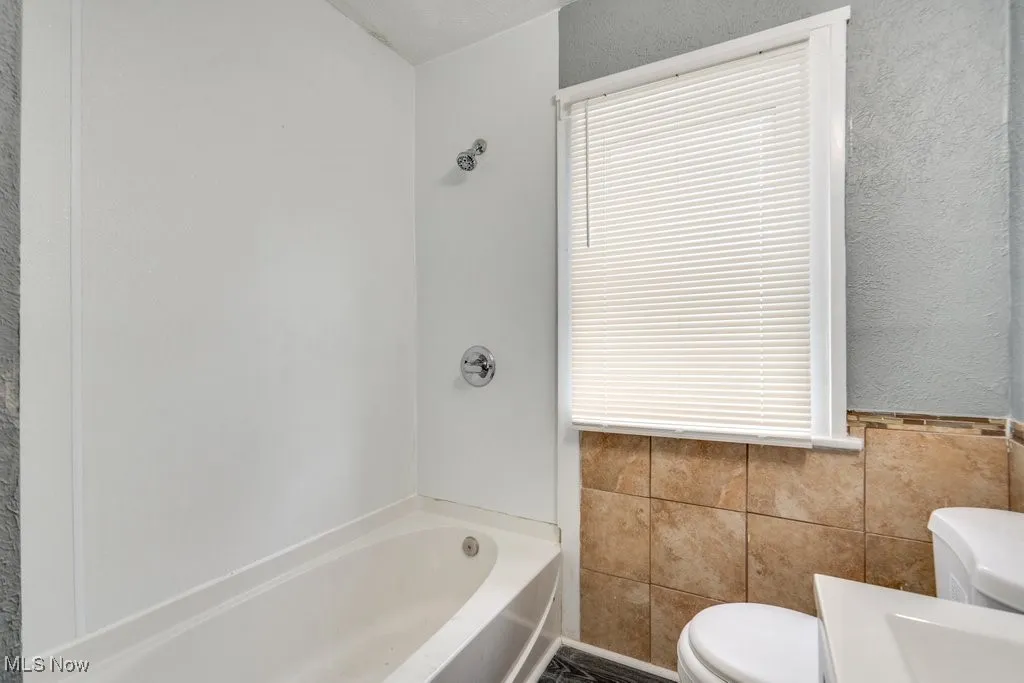 Bathroom featuring tile walls and shower / washtub combination