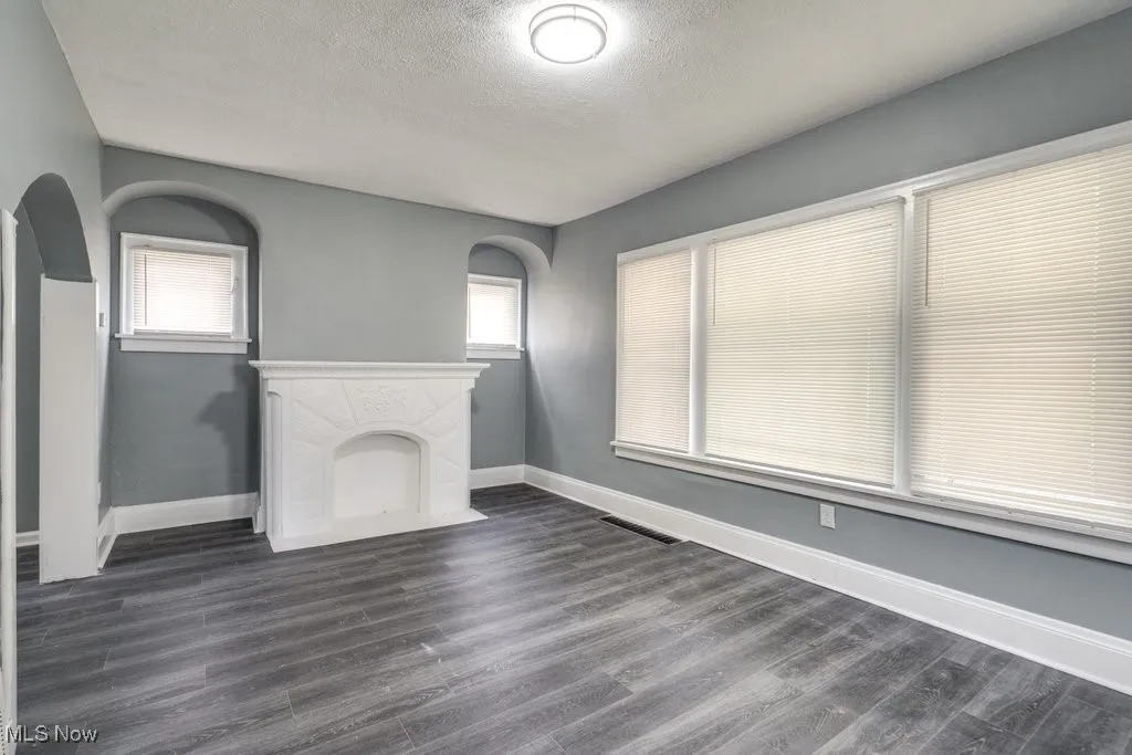 Unfurnished living room featuring plenty of natural light, a textured ceiling, and dark wood-type flooring