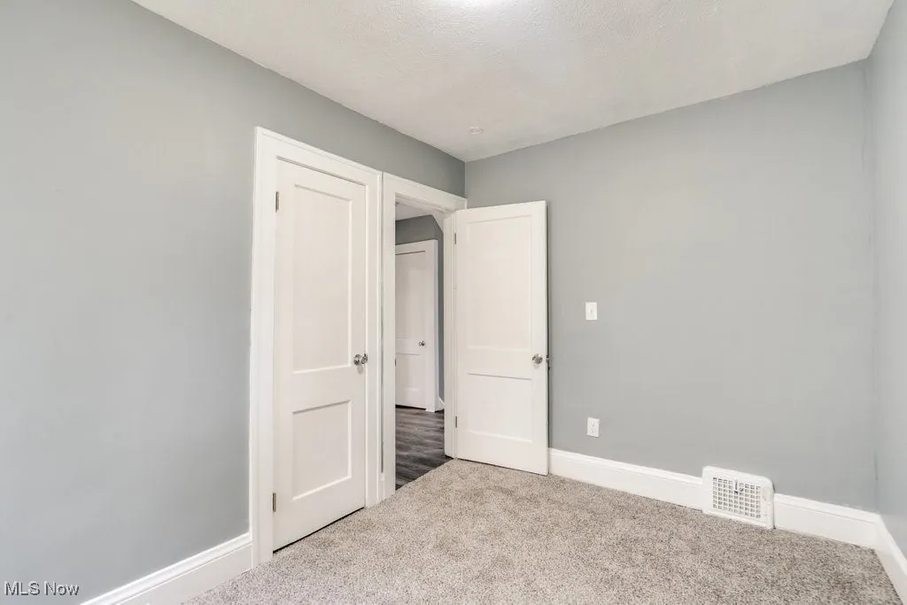 Unfurnished bedroom with carpet flooring and baseboards