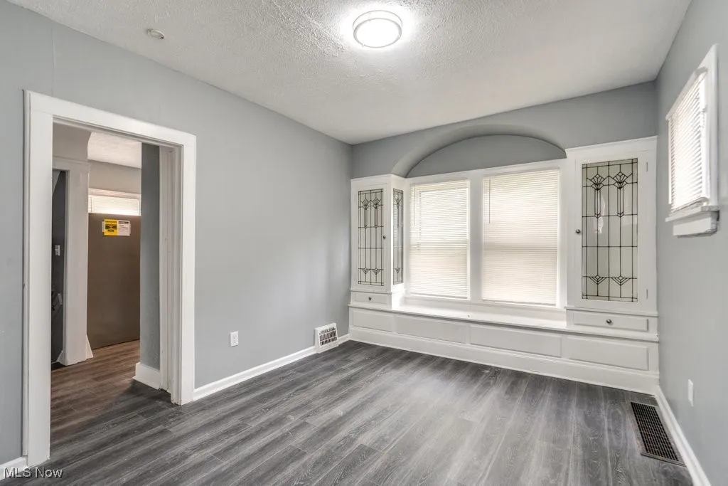 Empty room featuring dark wood-style flooring and a textured ceiling