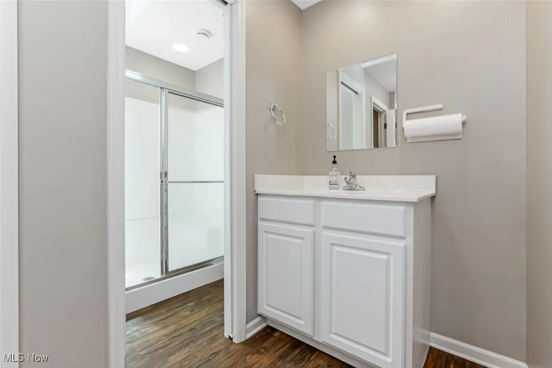 Full bathroom featuring a stall shower, vanity, and wood finished floors