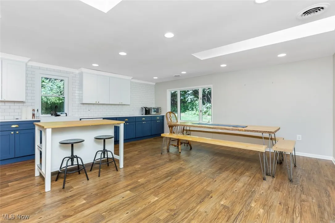 Kitchen with wood counters, blue cabinets, a skylight, and recessed lighting