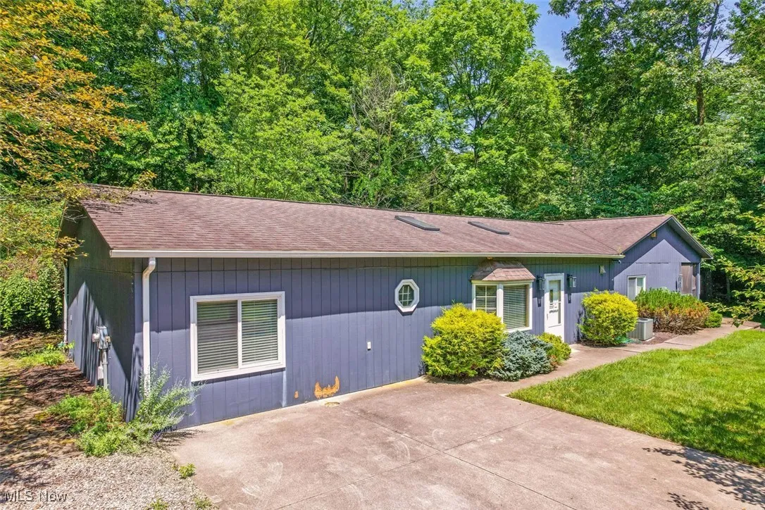 View of front of house with roof with shingles and concrete driveway