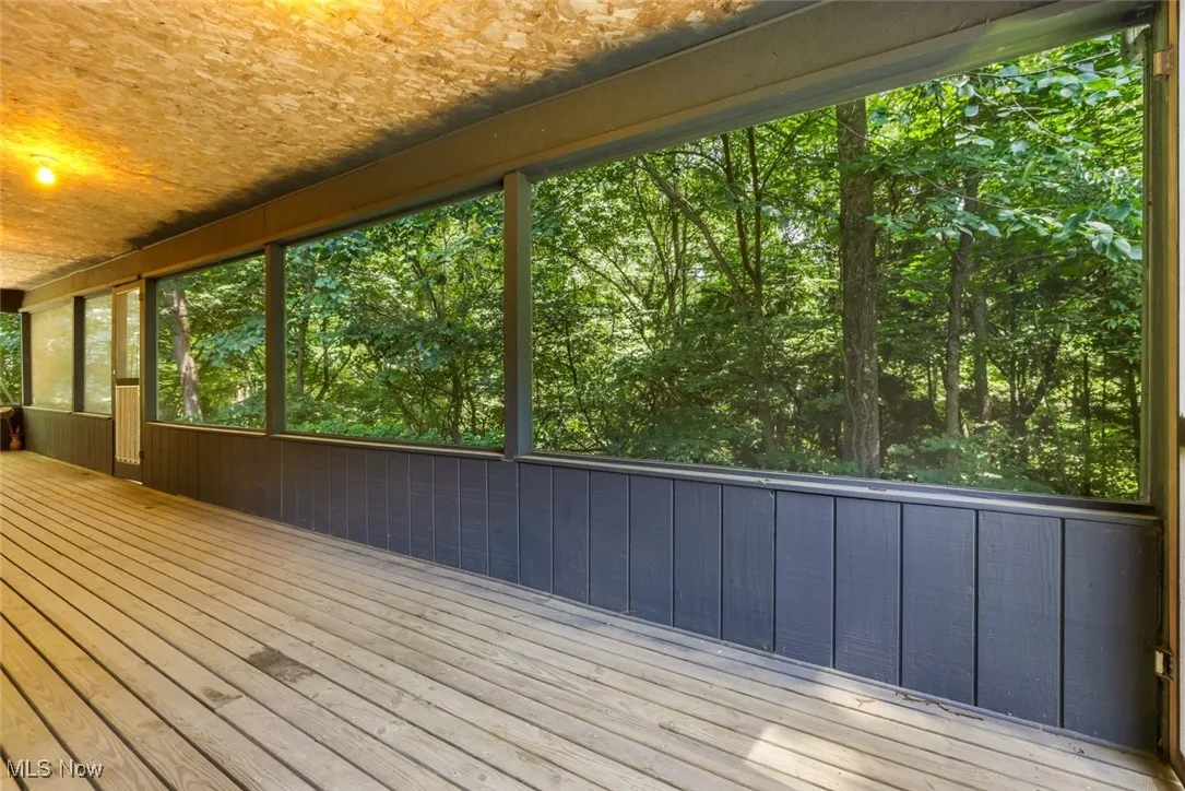 Unfurnished sunroom featuring view of wooded area