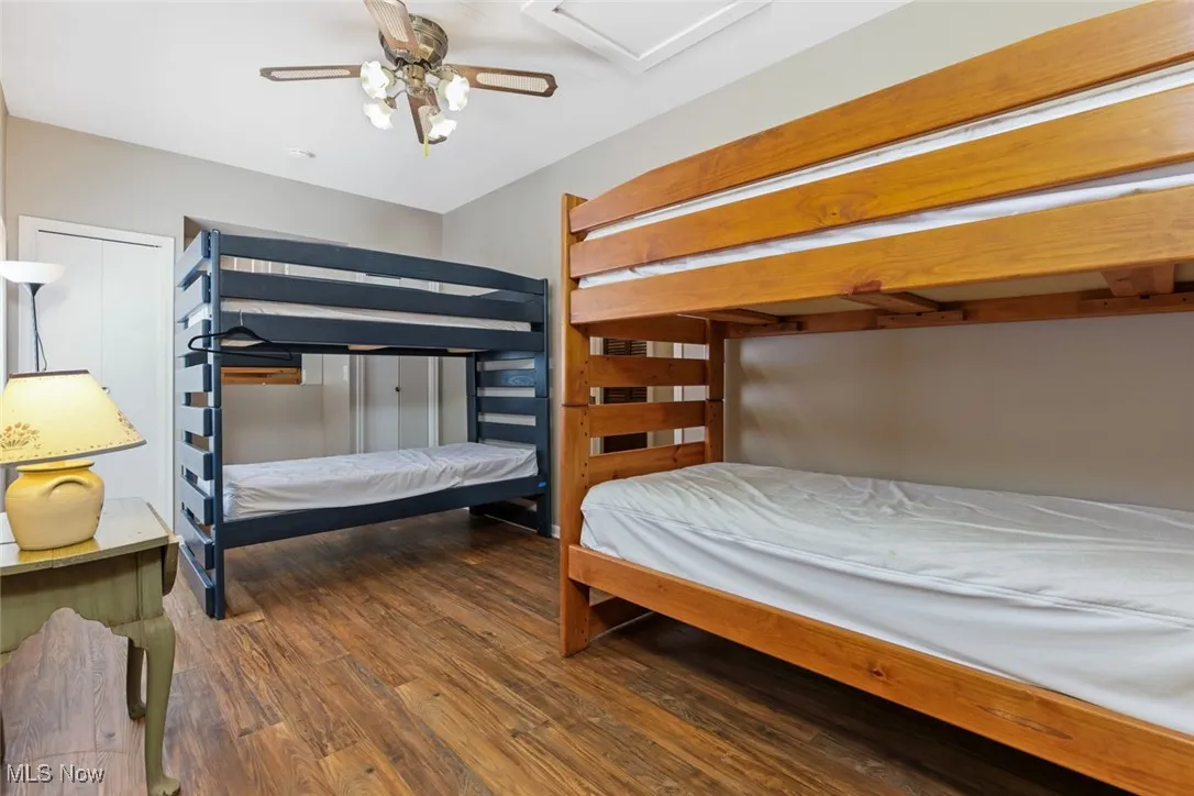 Bedroom with wood finished floors, attic access, and ceiling fan