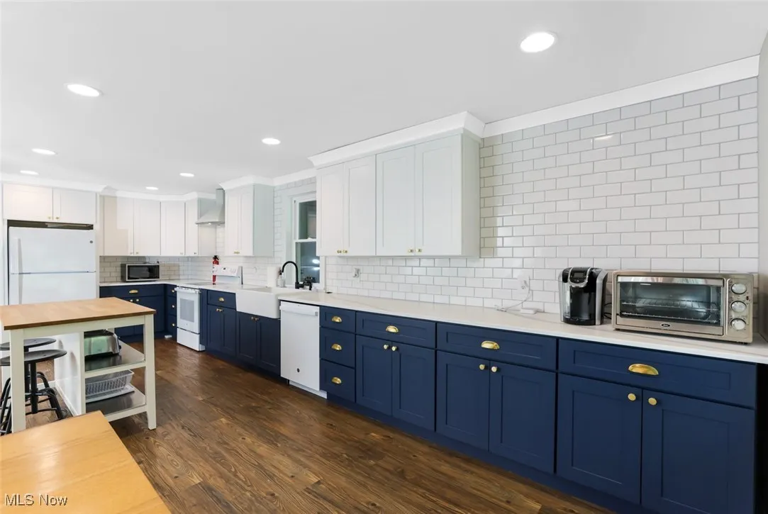 Kitchen with blue cabinets, white appliances, white cabinets, dark wood-style flooring, and recessed lighting