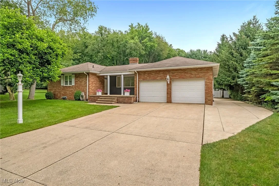 Single story home with brick siding, a garage, a chimney, and concrete driveway