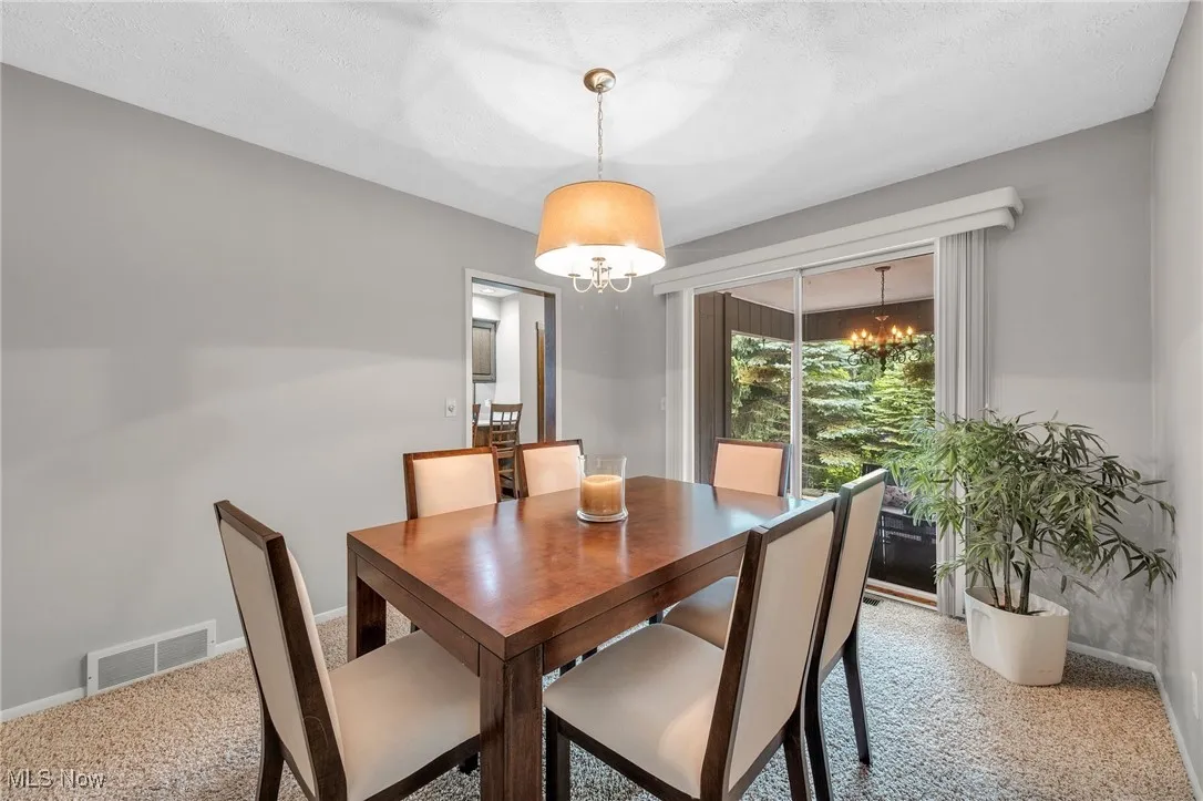 Carpeted dining area featuring a chandelier and baseboards