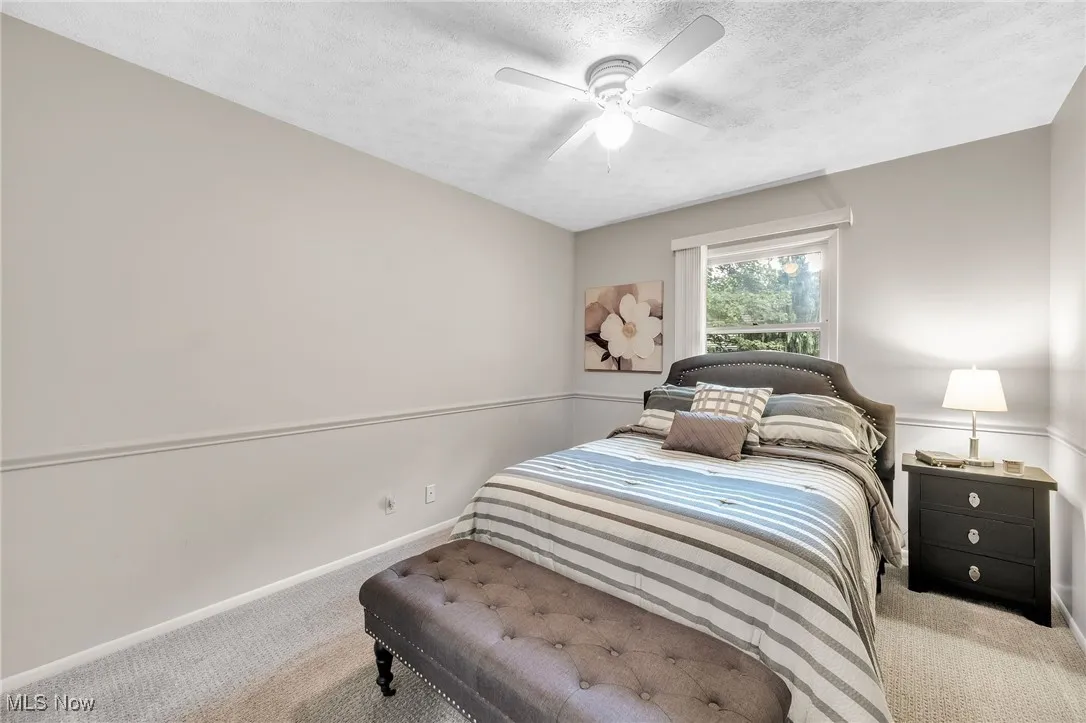 Bedroom with carpet floors, a textured ceiling, and ceiling fan