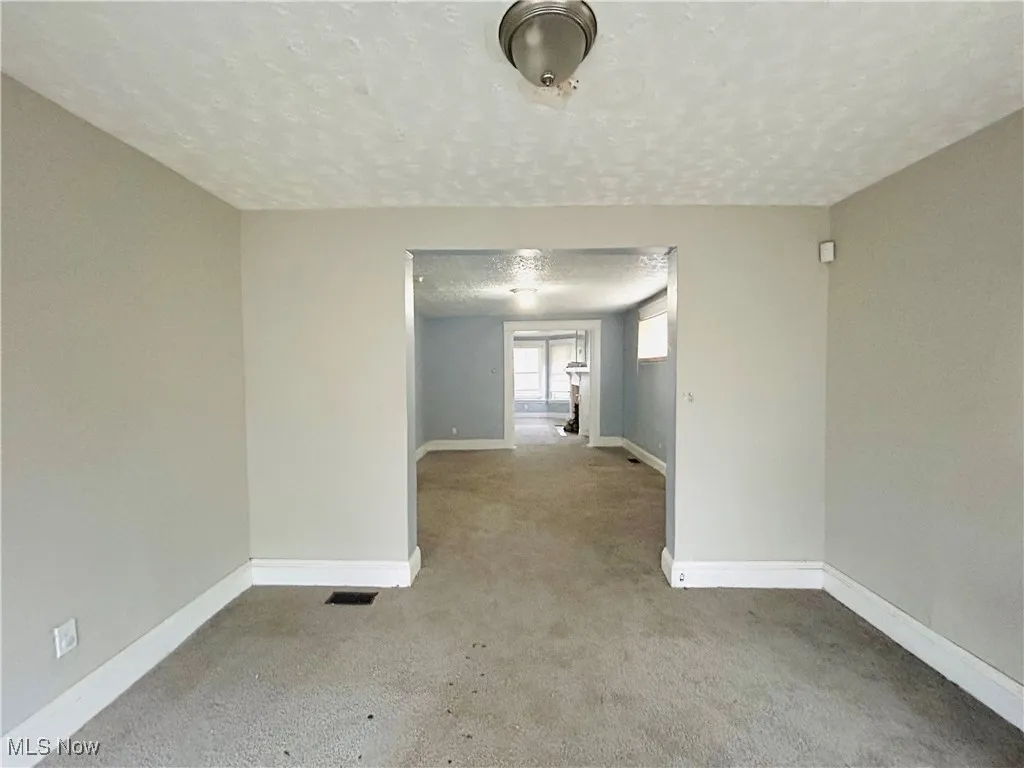 Empty room featuring visible vents, a textured ceiling, and baseboards