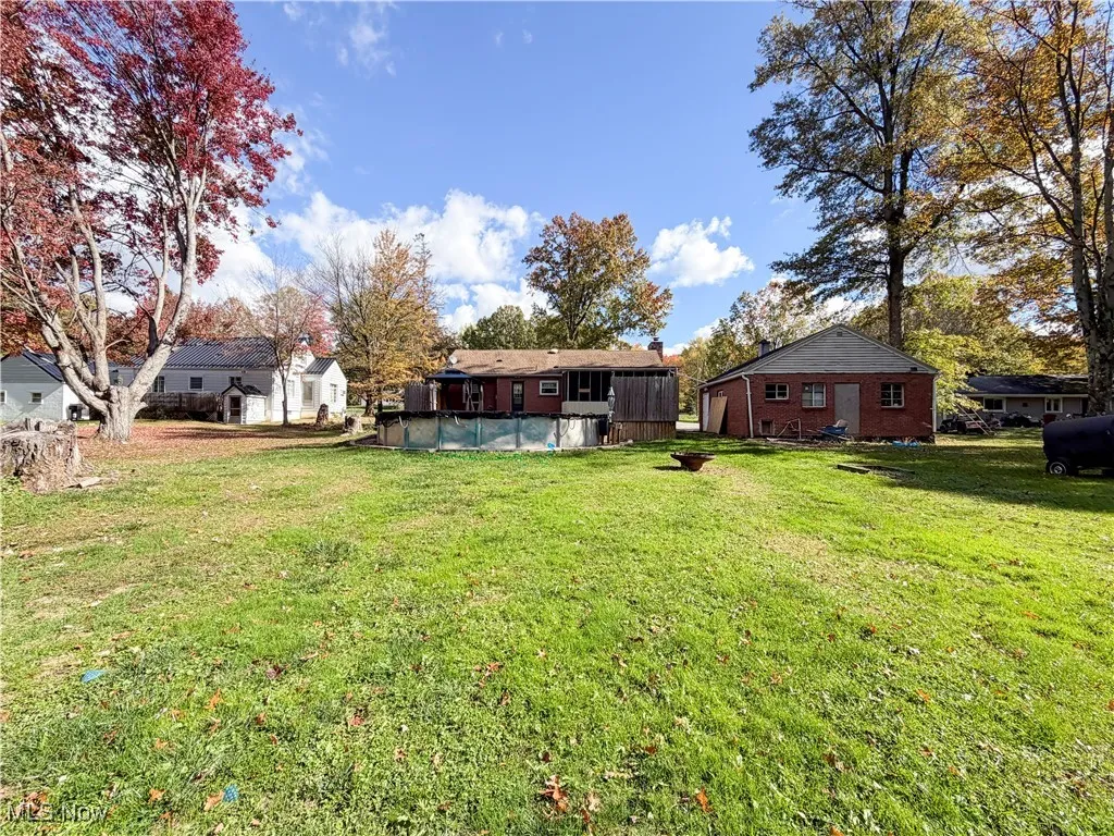 View of grassy yard with a covered pool and oil tank