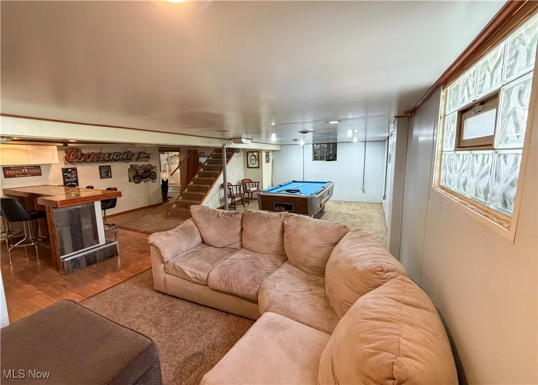 Living area with billiards table, stairway, light wood finished floors, and a dry bar