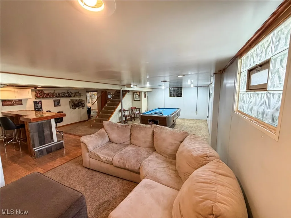 Living area featuring billiards, stairs, light wood finished floors, and a bar