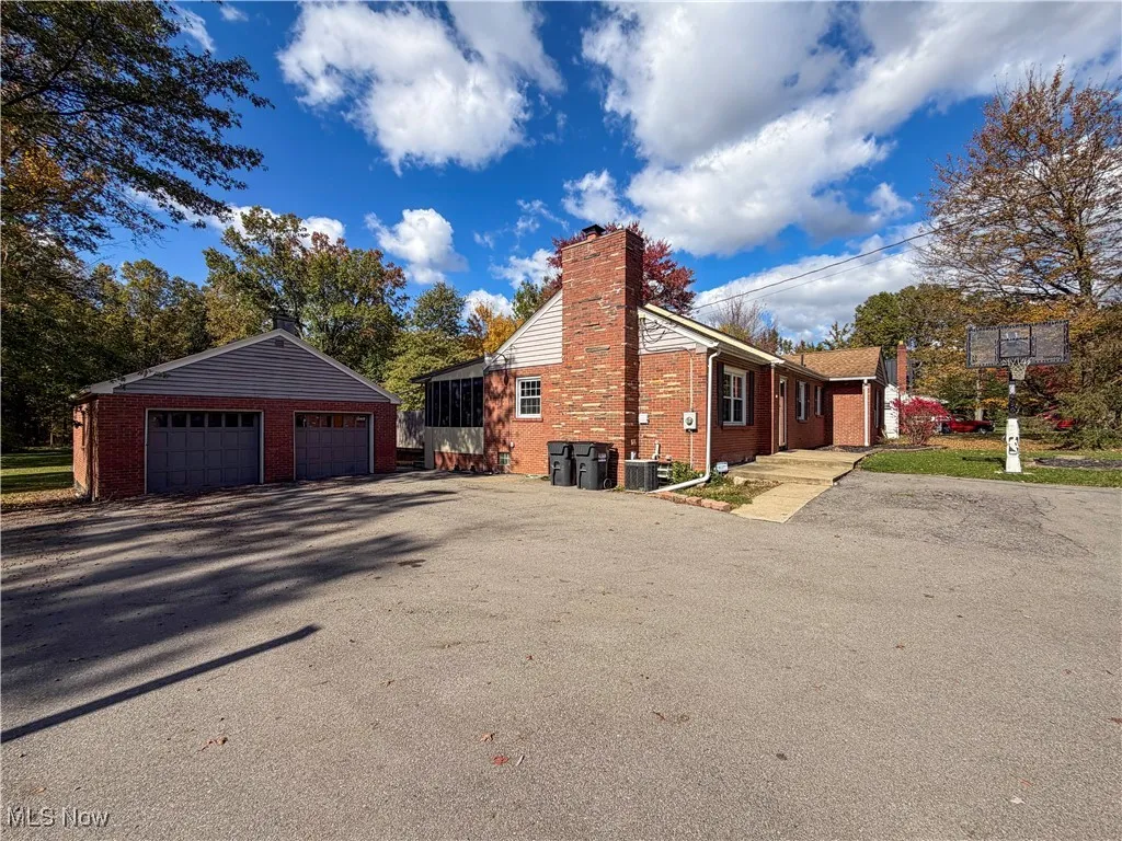 View of home's exterior with a chimney, an outdoor structure, brick siding, and a detached garage
