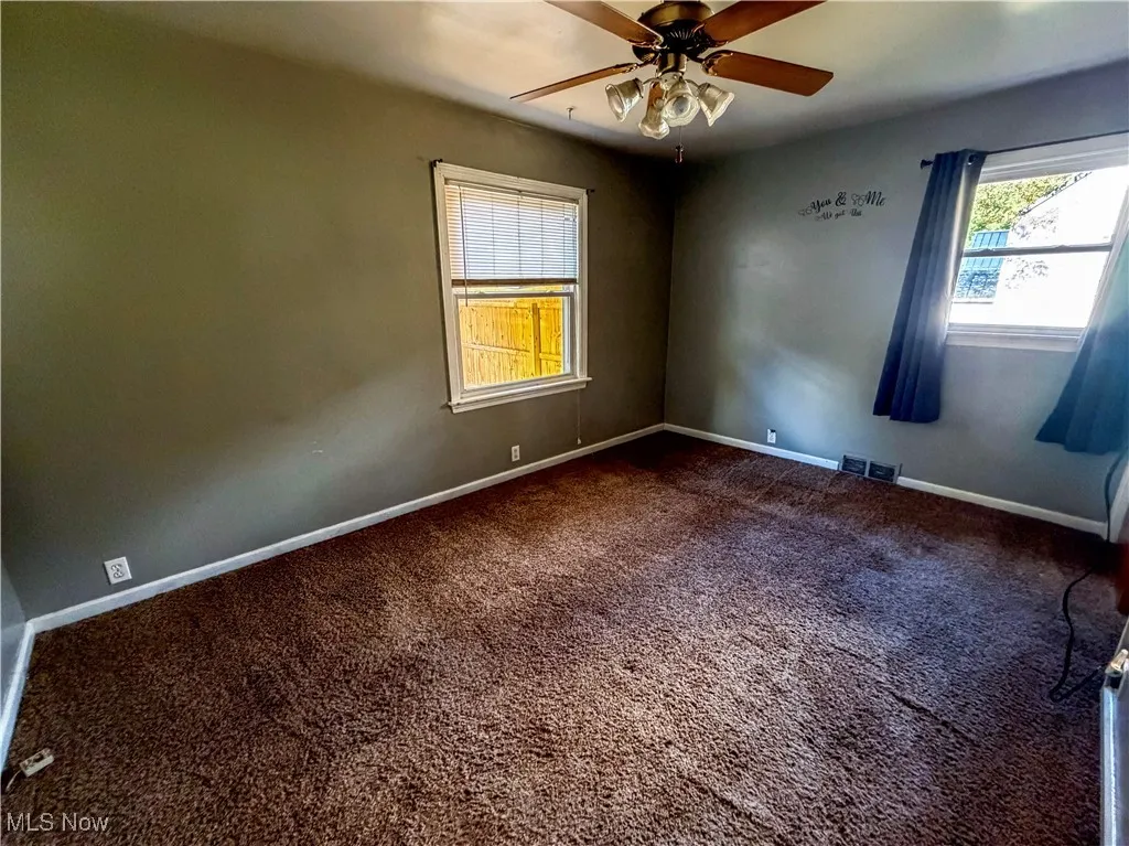 Spare room featuring dark colored carpet and ceiling fan