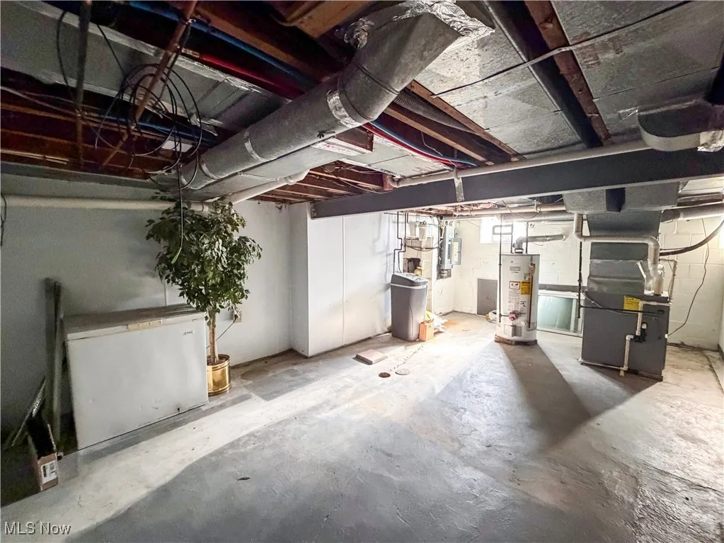 Unfinished basement with fridge, heating unit, a water softener, and gas water heater