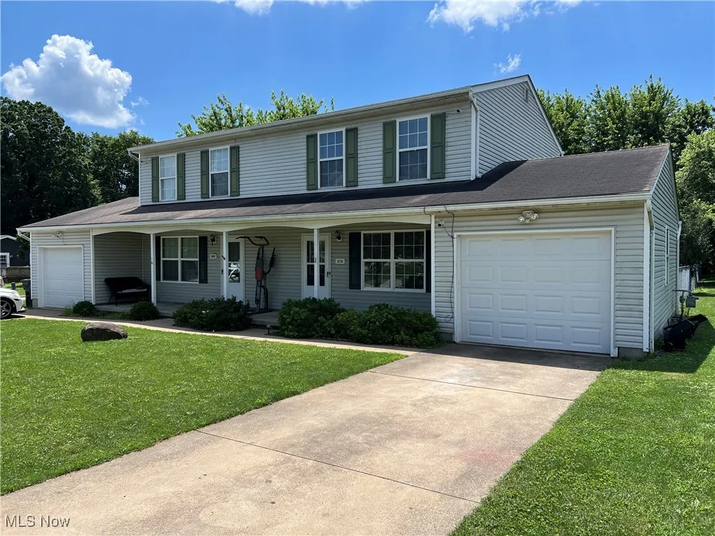 View of front of house with an attached garage, driveway, a front lawn, and covered porch
