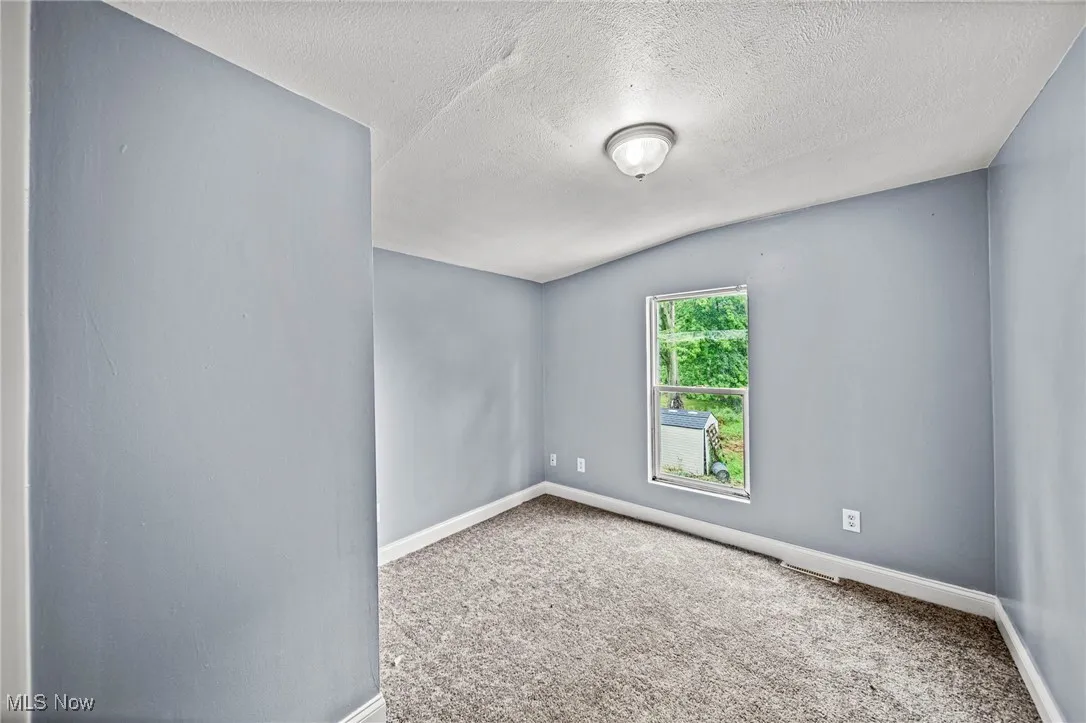 Carpeted empty room with baseboards and a textured ceiling