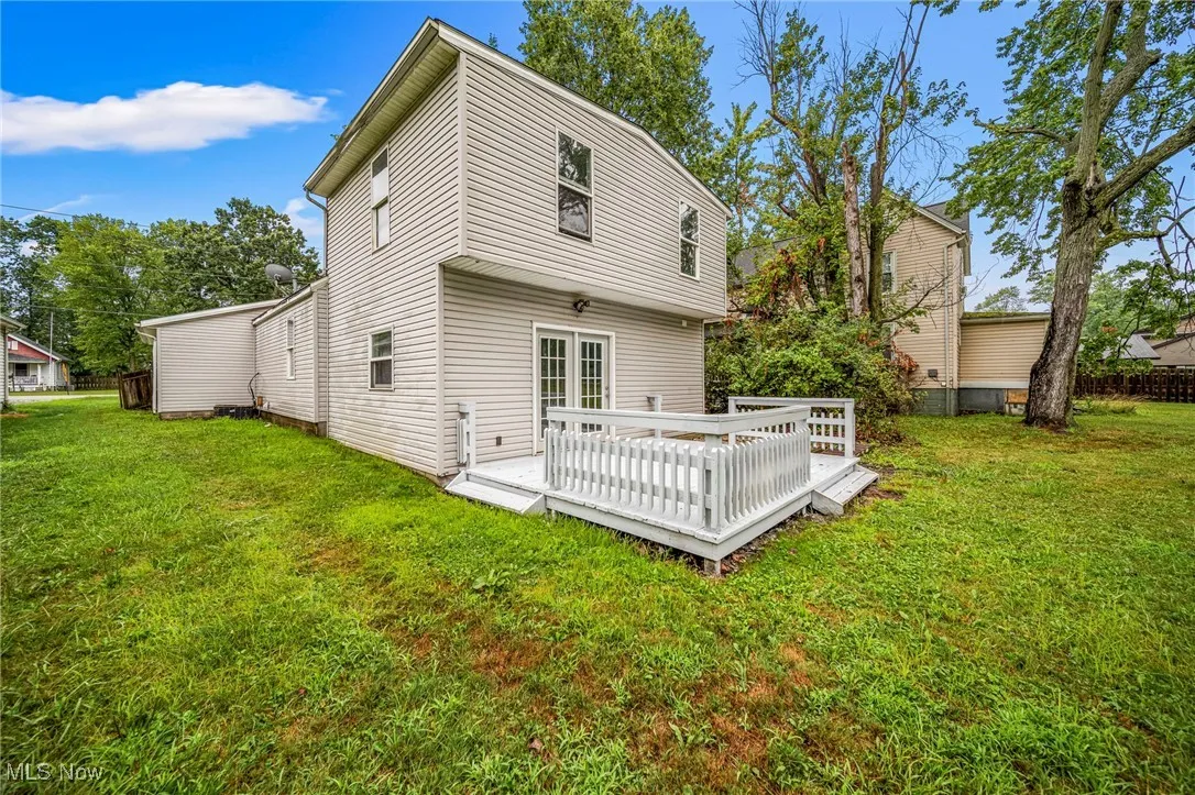 Rear view of house featuring a lawn and a wooden deck