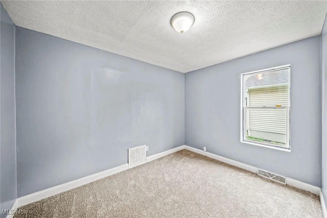Empty room with carpet and a textured ceiling