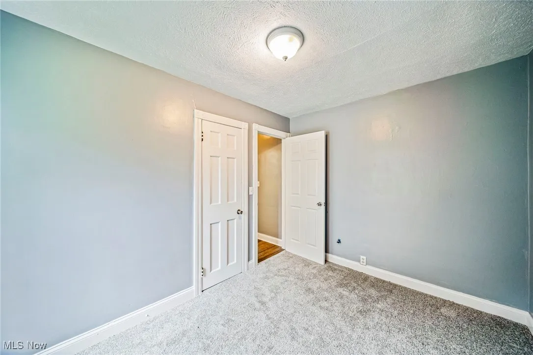 Carpeted spare room with a textured ceiling and baseboards