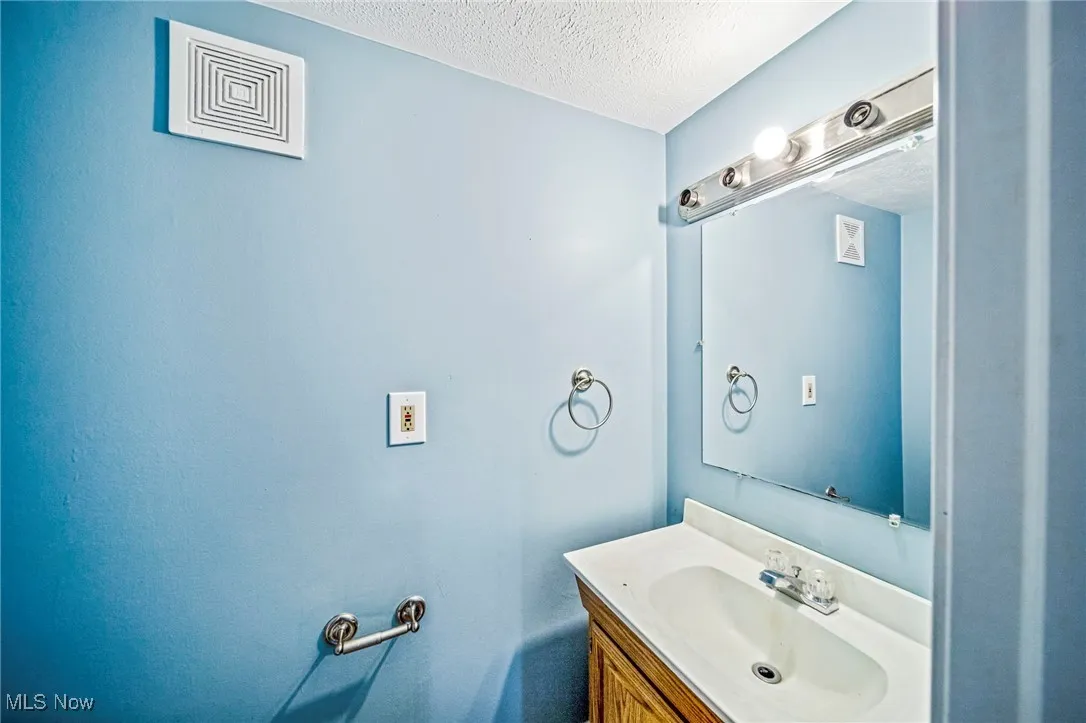 Bathroom featuring a textured ceiling and vanity