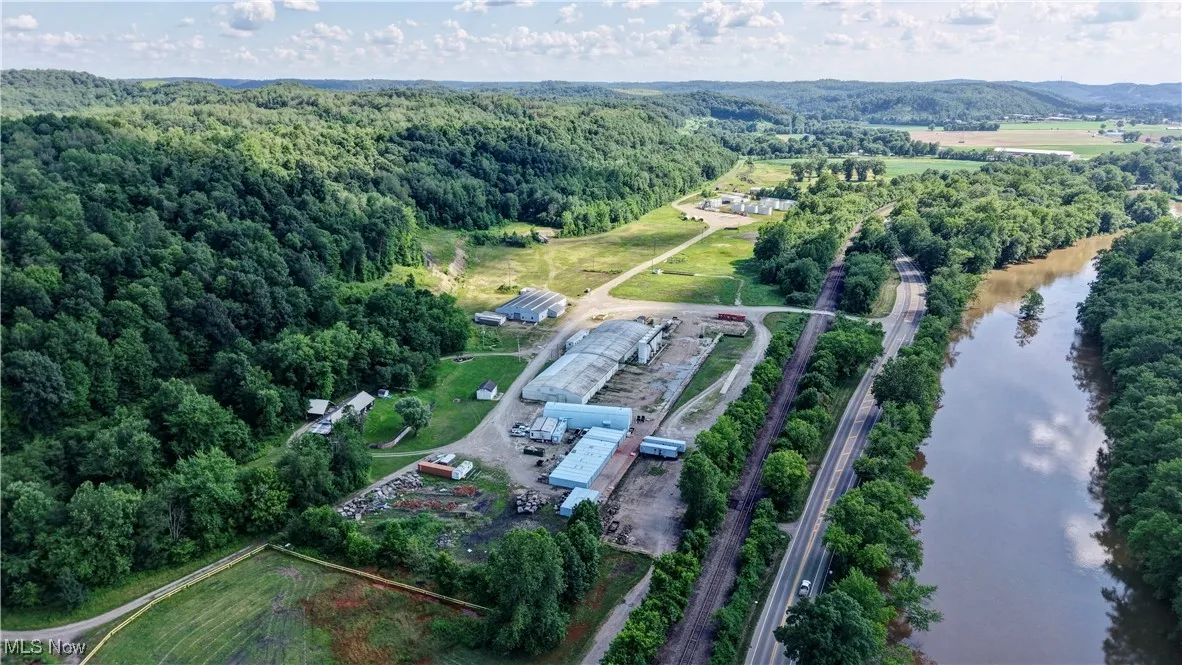 Aerial view of property and surrounding area featuring a nearby body of water and a heavily wooded area