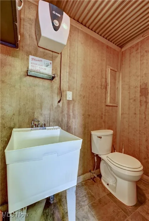 Half bath featuring toilet and wooden walls