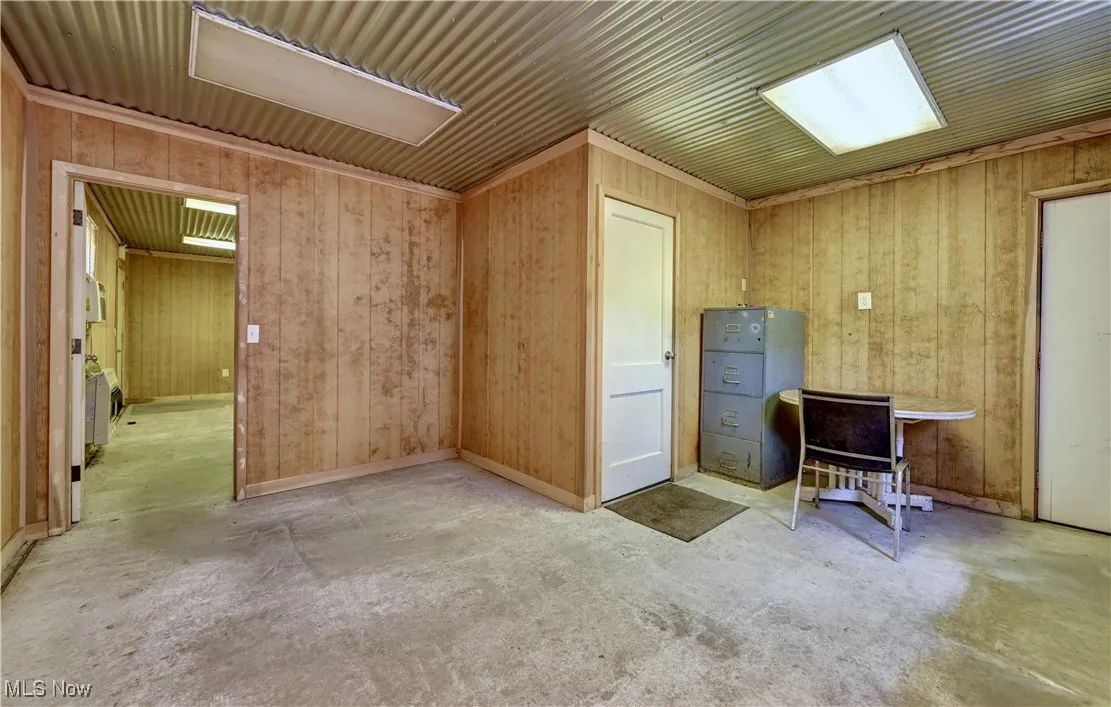 Miscellaneous room featuring concrete floors and wood walls