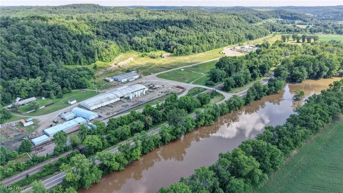 Aerial view of property's location featuring a forest and a nearby body of water