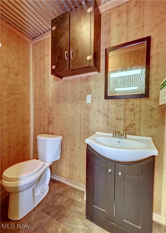 Half bath featuring vanity and wooden walls