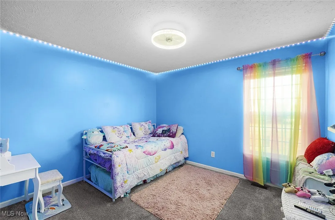 Carpeted bedroom with baseboards and a textured ceiling